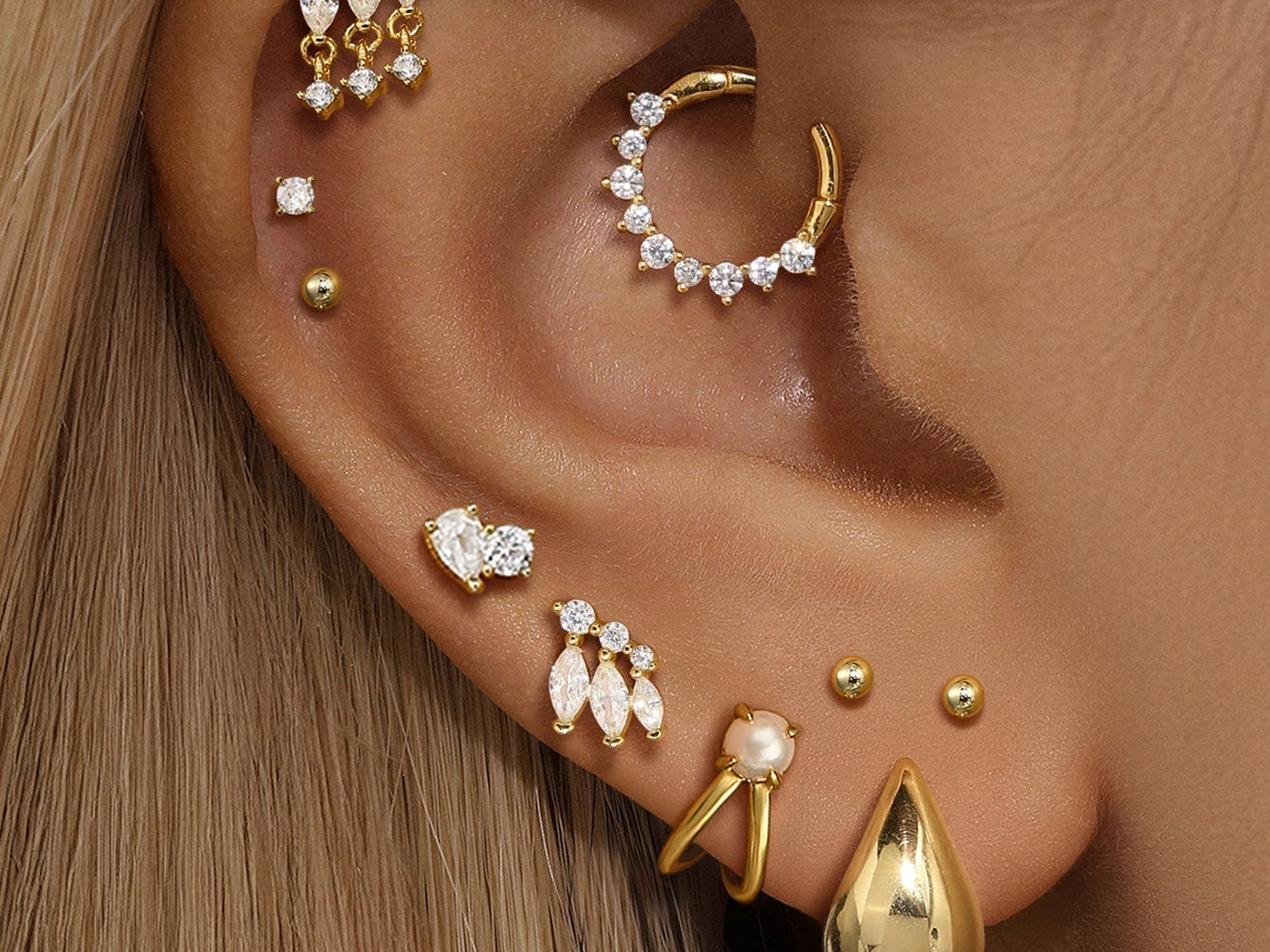 A stunning ear curation showing fully healed ear piercings with various Kosiner gold and diamond stud earrings and hoops.