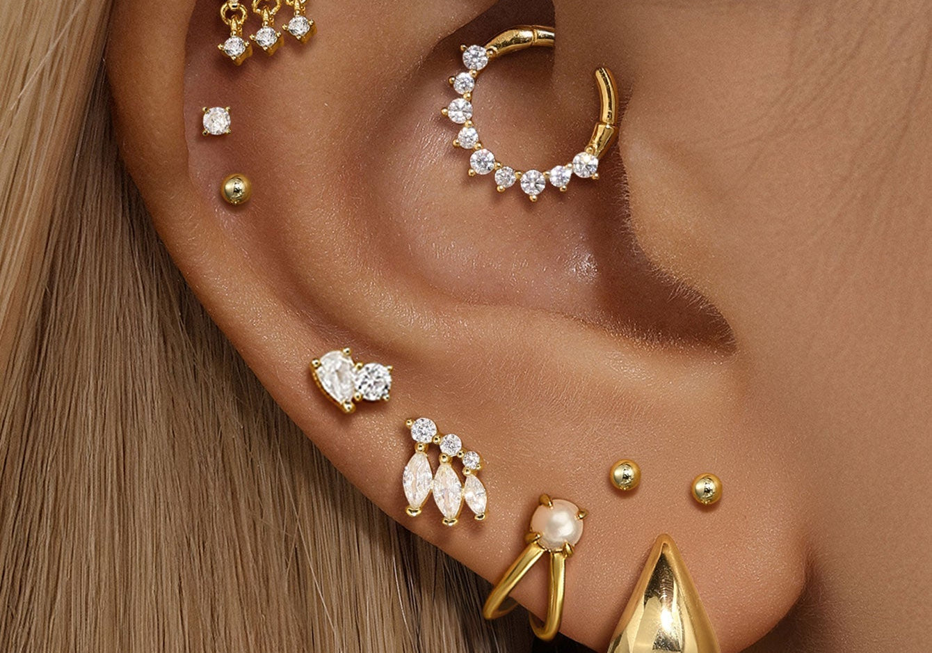 A stunning ear curation showing fully healed ear piercings with various Kosiner gold and diamond stud earrings and hoops.