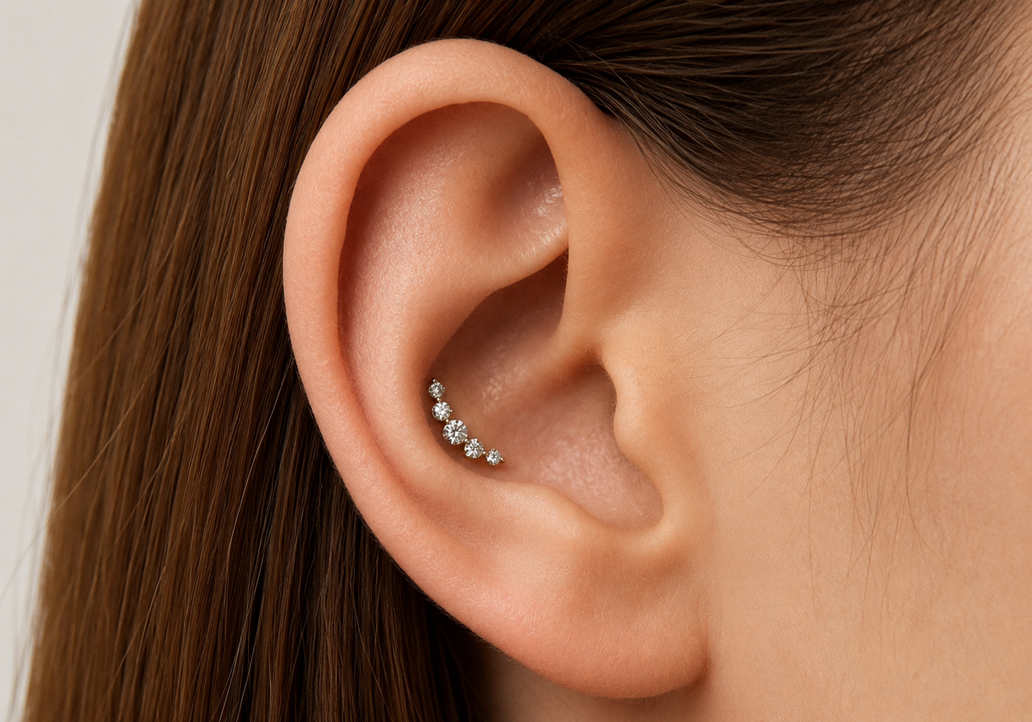 KOSINER conch piercing guide with gold flatback earrings on the central ear cartilage