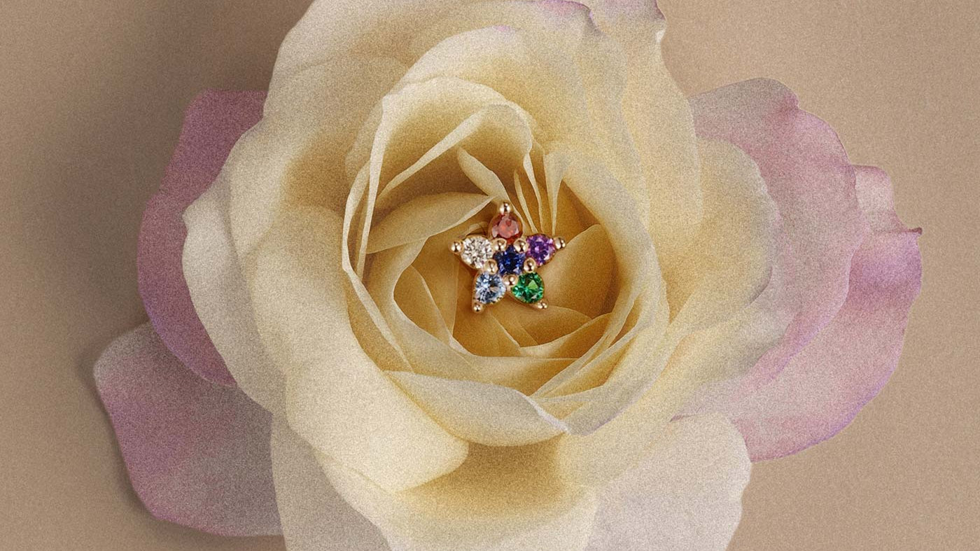 Colorful gemstone star stud earring in 14K gold nestled in cream rose for helix piercing jewelry inspiration