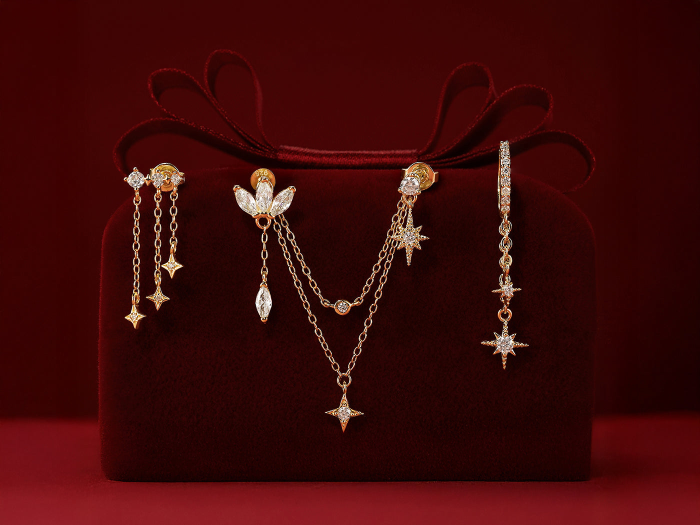 A stunning collection of gold chain earrings with star charms and studs, elegantly displayed on a luxurious red velvet box.