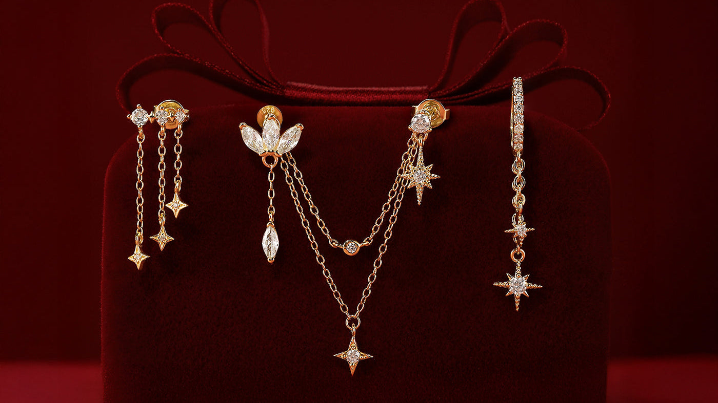 A stunning collection of gold chain earrings with star charms and studs, elegantly displayed on a luxurious red velvet box.