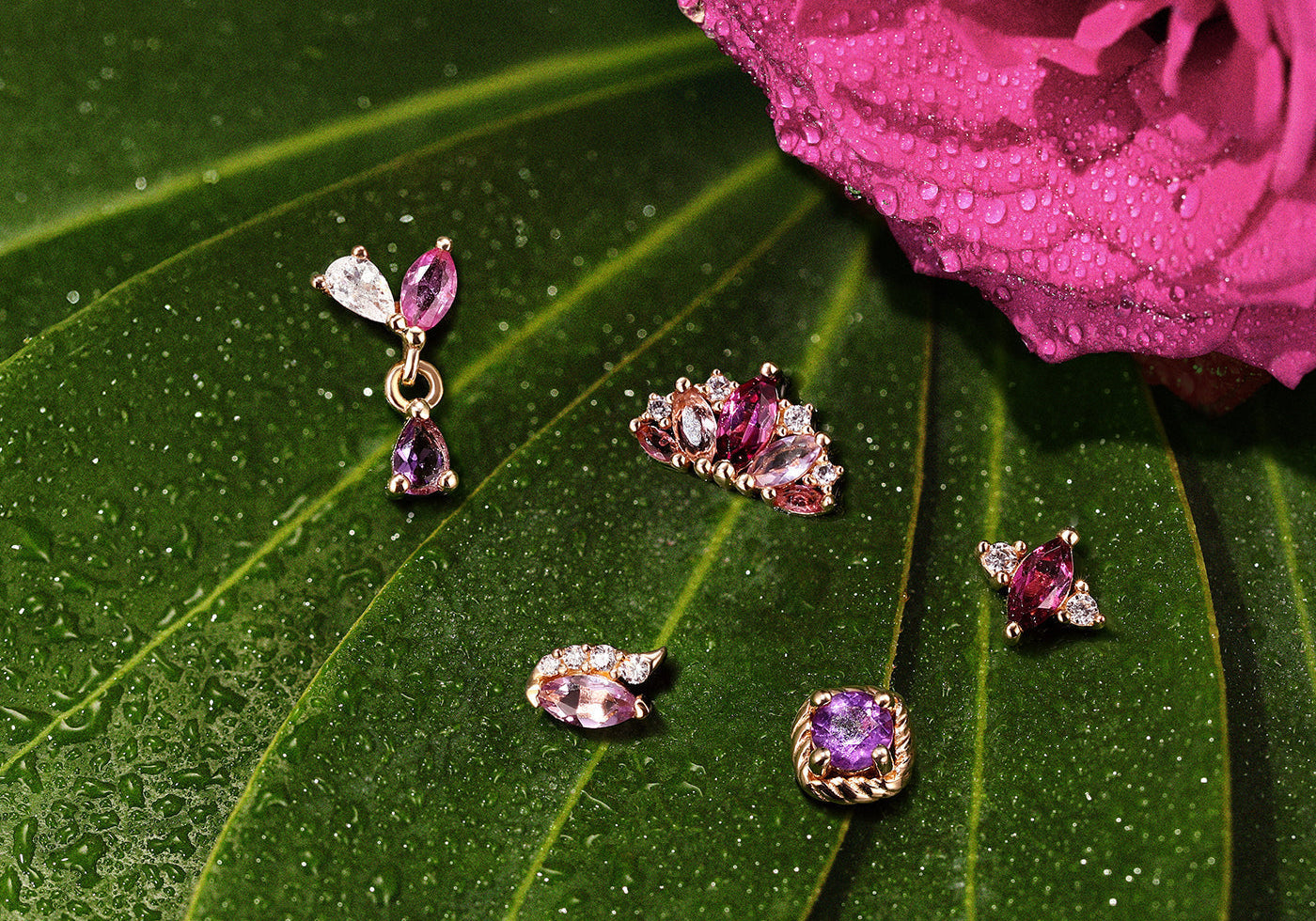 Collection of hypoallergenic titanium piercing studs featuring vibrant purple gemstones resting on a natural green leaf with water droplets.