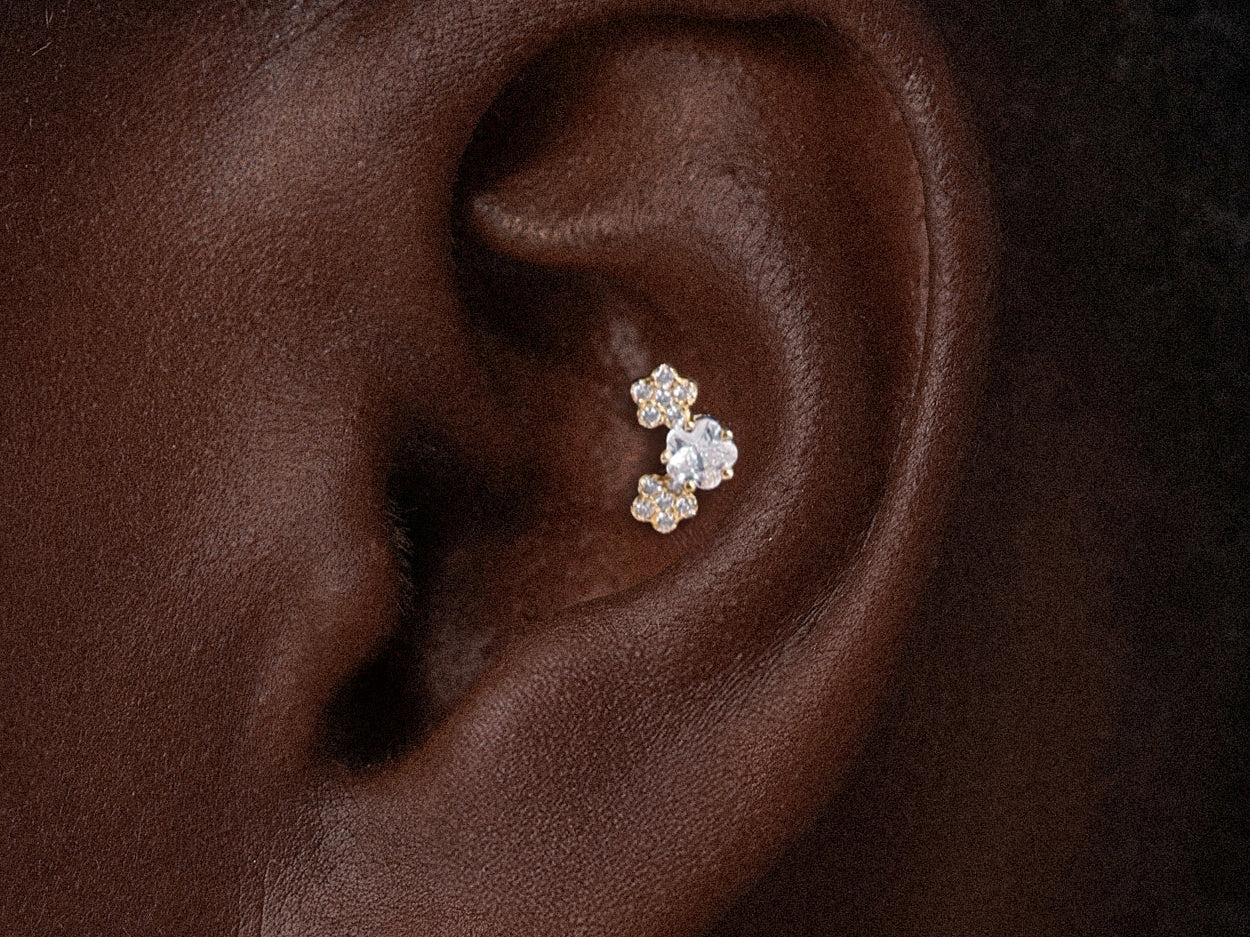Dainty gold floral conch earring featuring sparkling crystal petals worn in a central inner ear cartilage piercing.