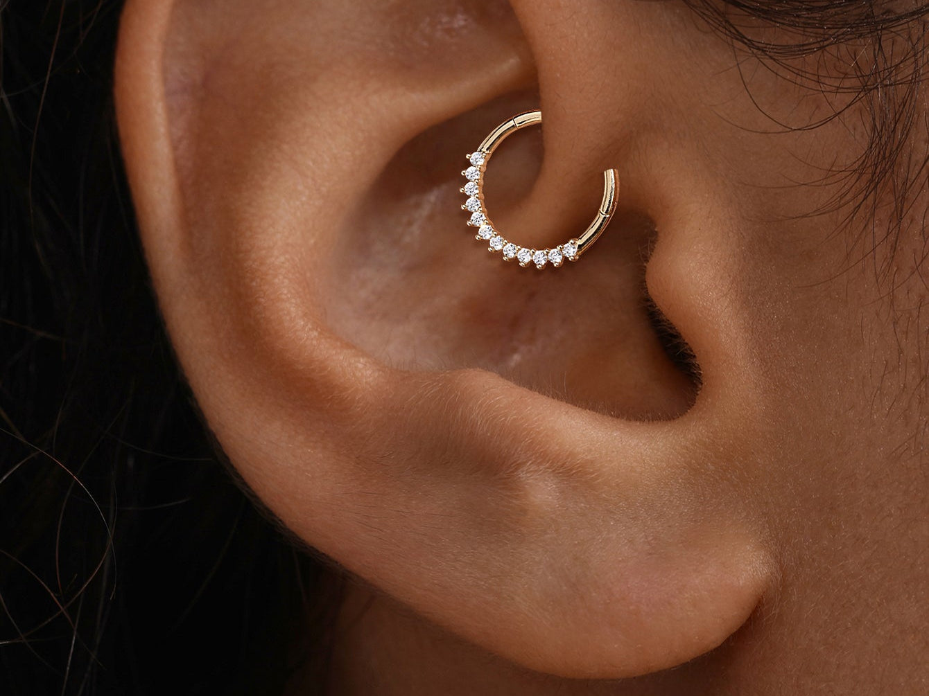 Close-up of a hypoallergenic 14K solid gold pave hoop earring worn comfortably in a daith ear piercing.