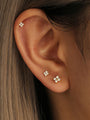 Three 18k gold plated 925 sterling silver floral stud earrings with cubic zirconia, shown on an ear.