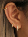 Gold plated sterling silver hoop earrings with cubic zirconia styled on ear.