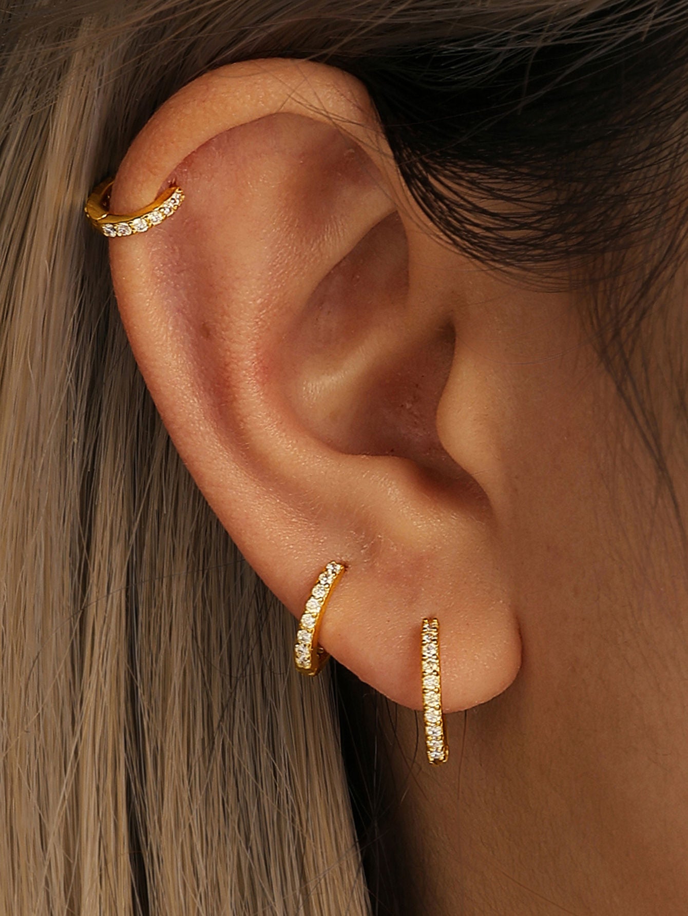 Gold plated sterling silver hoop earrings with cubic zirconia styled on ear.
