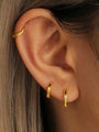 Three 18K gold plated sterling silver hoop earrings in multi-sizes shown on an ear demonstrating placement.