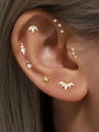 Model showcasing assorted gold plated sterling silver CZ stud earrings, including starburst and lotus designs.