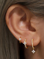 Gold plated sterling silver hoop earrings with pave cubic zirconia floral charms on model's ear.