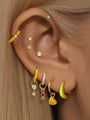 Multiple gold-plated sterling silver ear piercings with cubic zirconia, including solitaire studs and charms for styling.