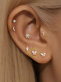 14K solid gold butterfly piercing studs with AAAAA cubic zirconia, styled in an ear stack.