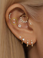 14K solid gold mini pendant ear piercing stud with two prong-set cubic zirconia stones, shown on earlobe.