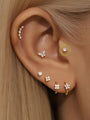 14K solid gold tiny ear piercing stud with 3.6mm cubic zirconia on ear, part of a stylish stack.