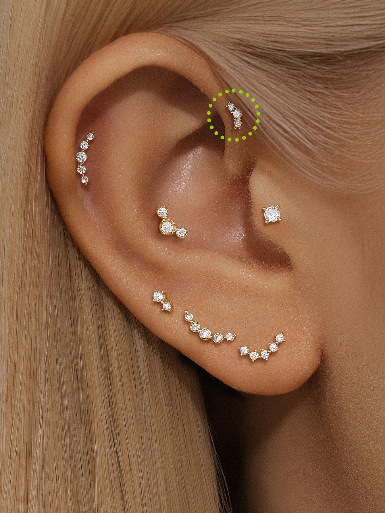 14K gold curved stud earring with three pave cubic zirconia stones, shown on ear piercing.