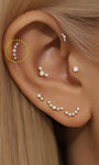 14K solid gold pave ear stud featuring a curve of clear cubic zirconia stones. Worn on helix piercing.