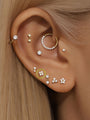 14K solid gold four flower ear piercing stud with clear cubic zirconia stones, styled on ear with multiple piercings.