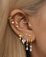 Collection of gold sterling silver earrings with cubic zirconia, including hoops and studs, styled on an ear.