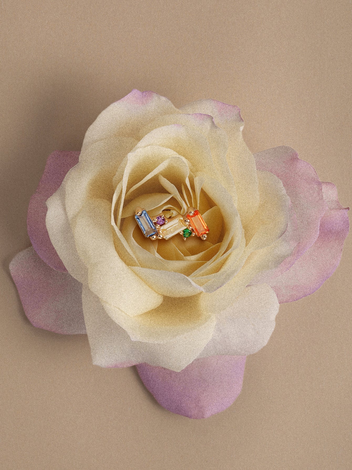 KOSINER 14K solid gold colorful baguette rainbow cluster flat back stud placed on pale gradient rose, vibrant multi cubic zirconia cartilage ear jewelry