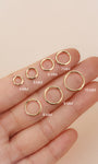KOSINER 14K solid gold minimalist clicker hoop size collection displayed on fingertip, available diameters 4mm,5mm,6mm,7mm,8mm,9mm,10mm, polished seamless hinged ring design for cartilage and lobe piercings
