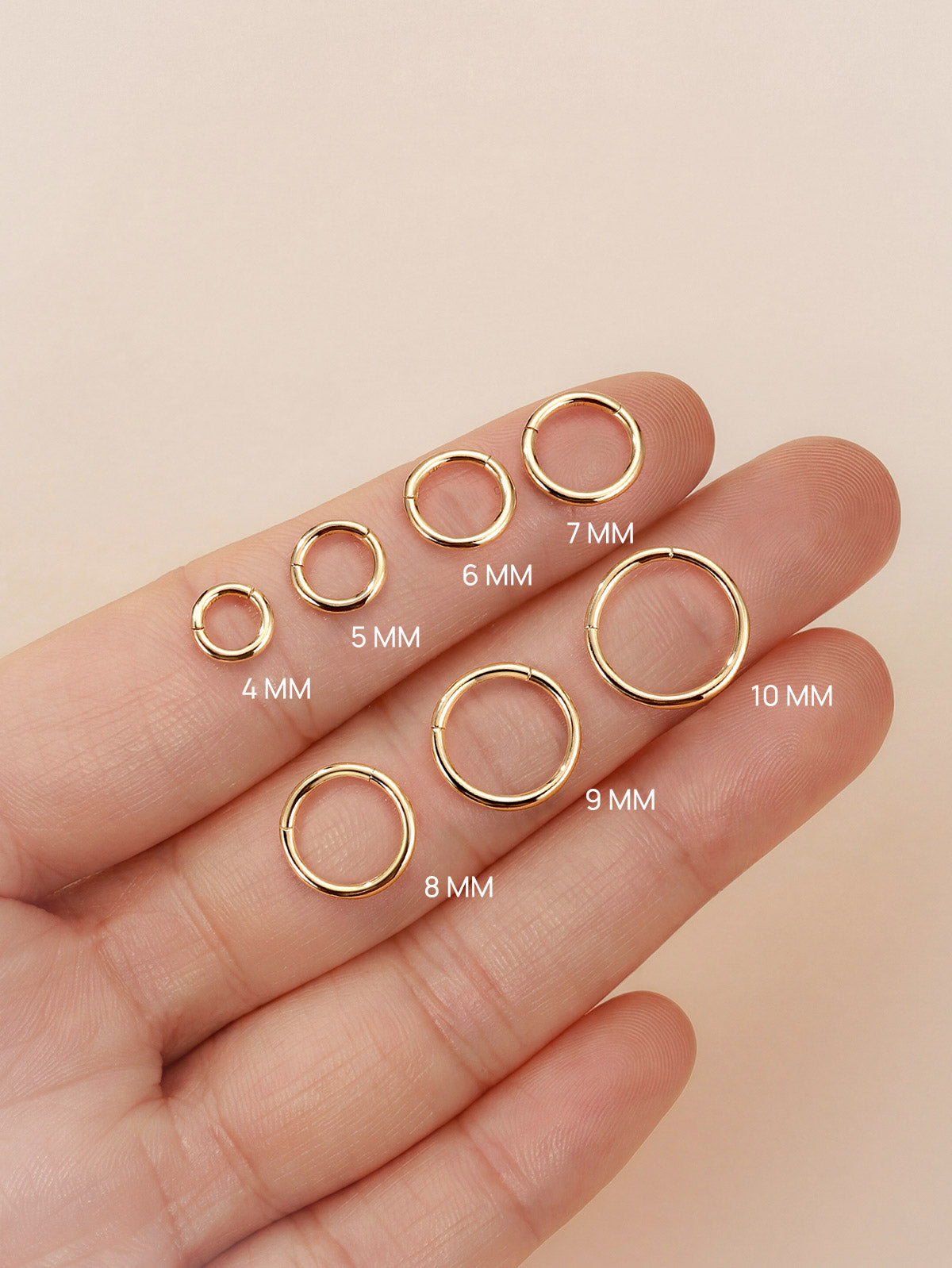 KOSINER 14K solid gold minimalist clicker hoop size collection displayed on fingertip, available diameters 4mm,5mm,6mm,7mm,8mm,9mm,10mm, polished seamless hinged ring design for cartilage and lobe piercings
