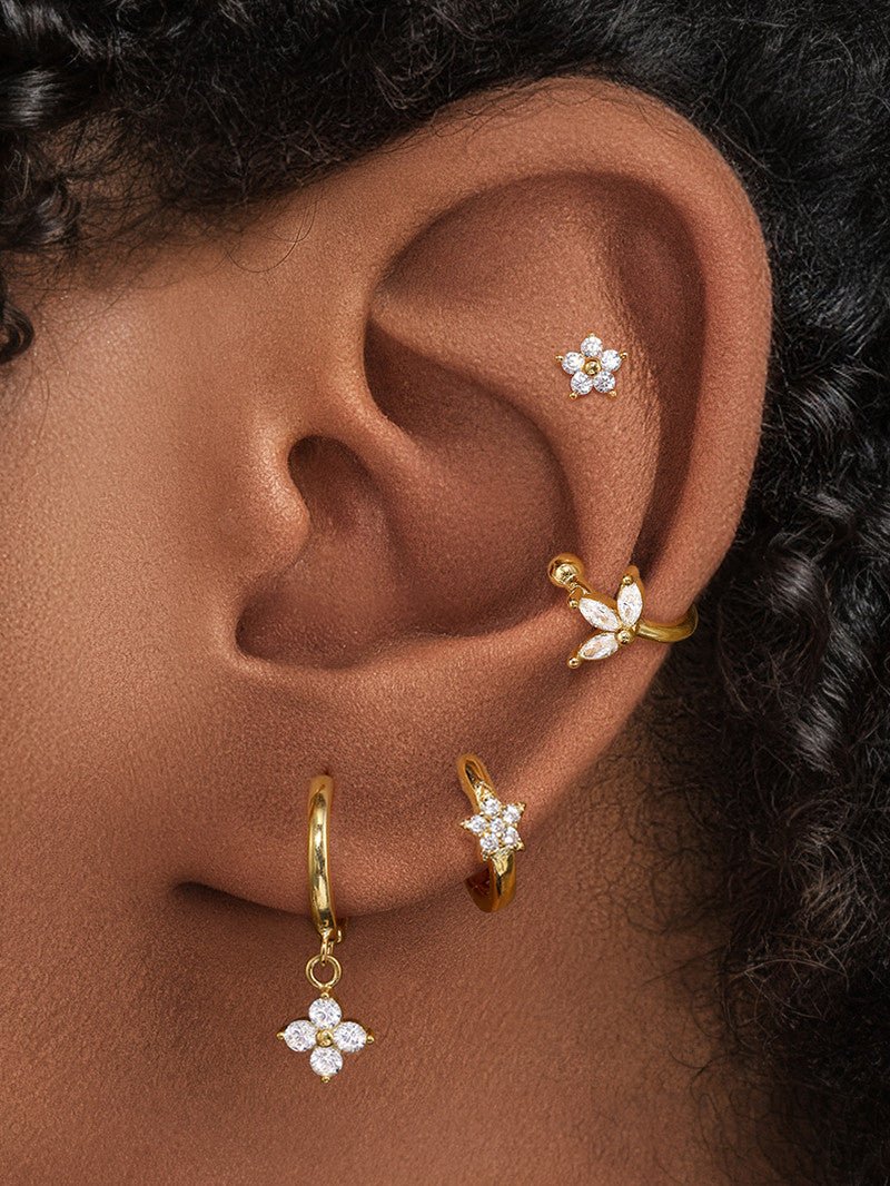 Gold-plated 925 sterling silver ear piercings showcasing flower stud, leaf cuff, and flower dangle hoop with CZ stones.