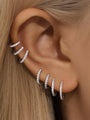 Silver huggie hoop earrings and ear cuffs with cubic zirconia, styled on a human ear. Shows elegant stacking options.
