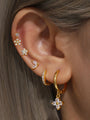 Gold sterling silver earrings with flower, butterfly, and hoop designs with zircon stones, worn on ear for styling.