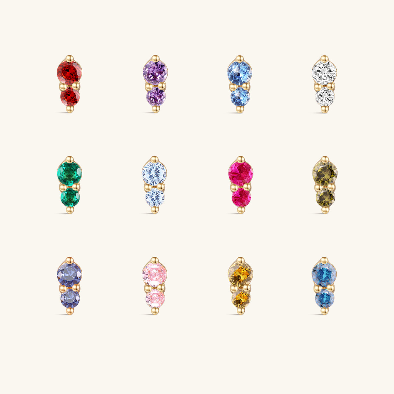 Complete 12-month dual birthstone flat back stud collection on off-white background, 14K gold prong-set two-stone design, each row corresponds to a monthly birthstone CZ hue from January Garnet to December Tanzanite