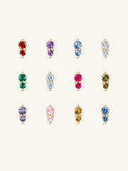 Complete 12-month dual birthstone flat back stud collection on off-white background, 14K gold prong-set two-stone design, each row corresponds to a monthly birthstone CZ hue from January Garnet to December Tanzanite
