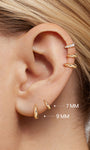 Close-up ear stacking photo showing KOSINER 14K solid gold C-shape flat back stud worn on helix piercing, paired with pave crystal matching style for delicate layered cartilage ear styling