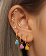 Gold plated sterling silver ear piercing stud with cubic zirconia flower and leaf accents, styled on ear with hoops.