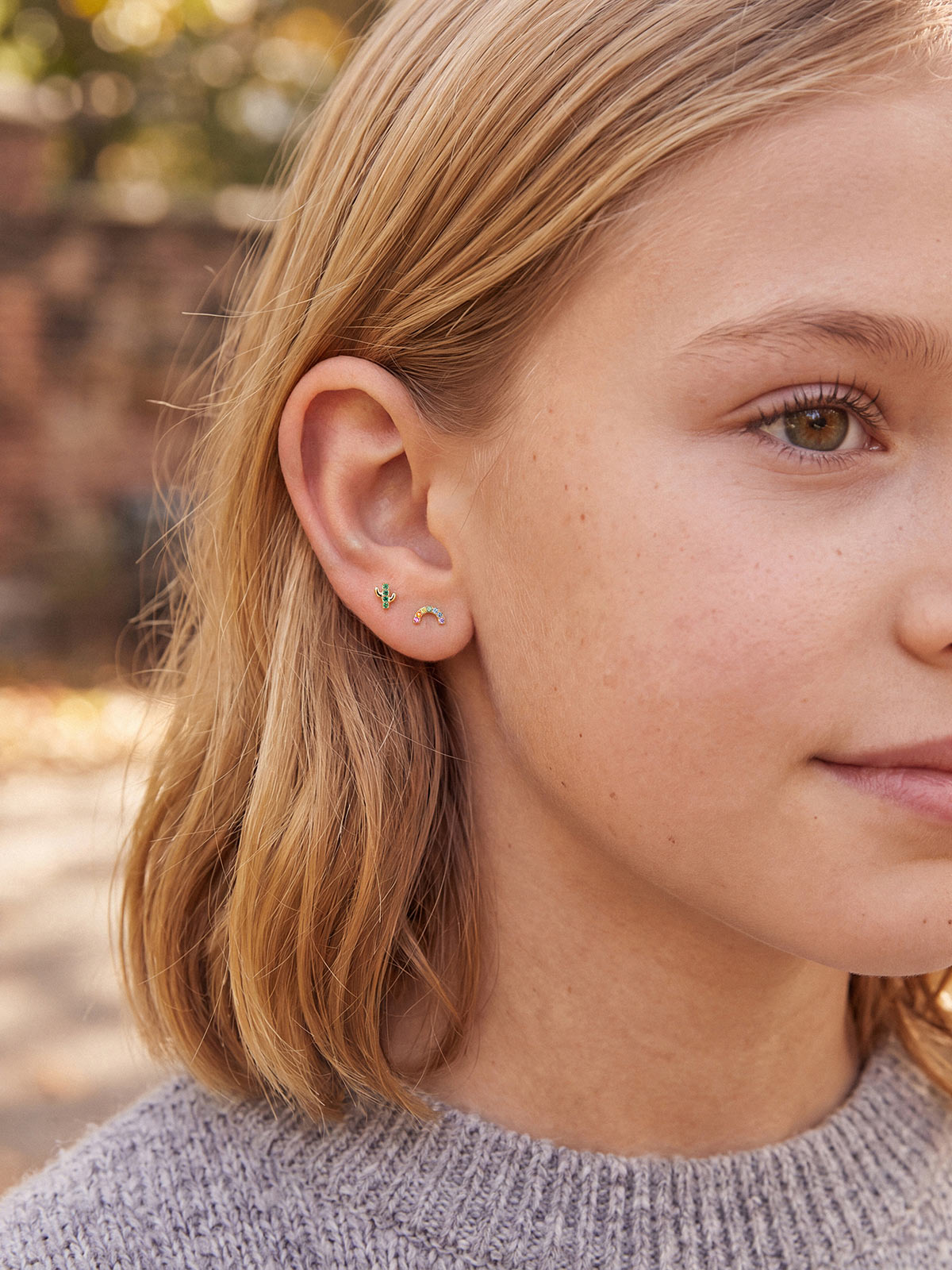 Model wearing the Little Wonder 14K gold rainbow flat back stud in an ear stack