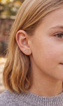 Close-up of Little Wonder gold flower flat back stud styled on the ear