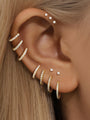 Gold huggie earrings & studs with CZ diamonds, showing scale & styling on ear.