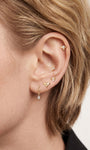 Model wearing 14K solid gold honeycomb flat back stud on inner helix, curated layered ear stack with assorted gold cartilage piercings, blonde hair ear styling lifestyle photo