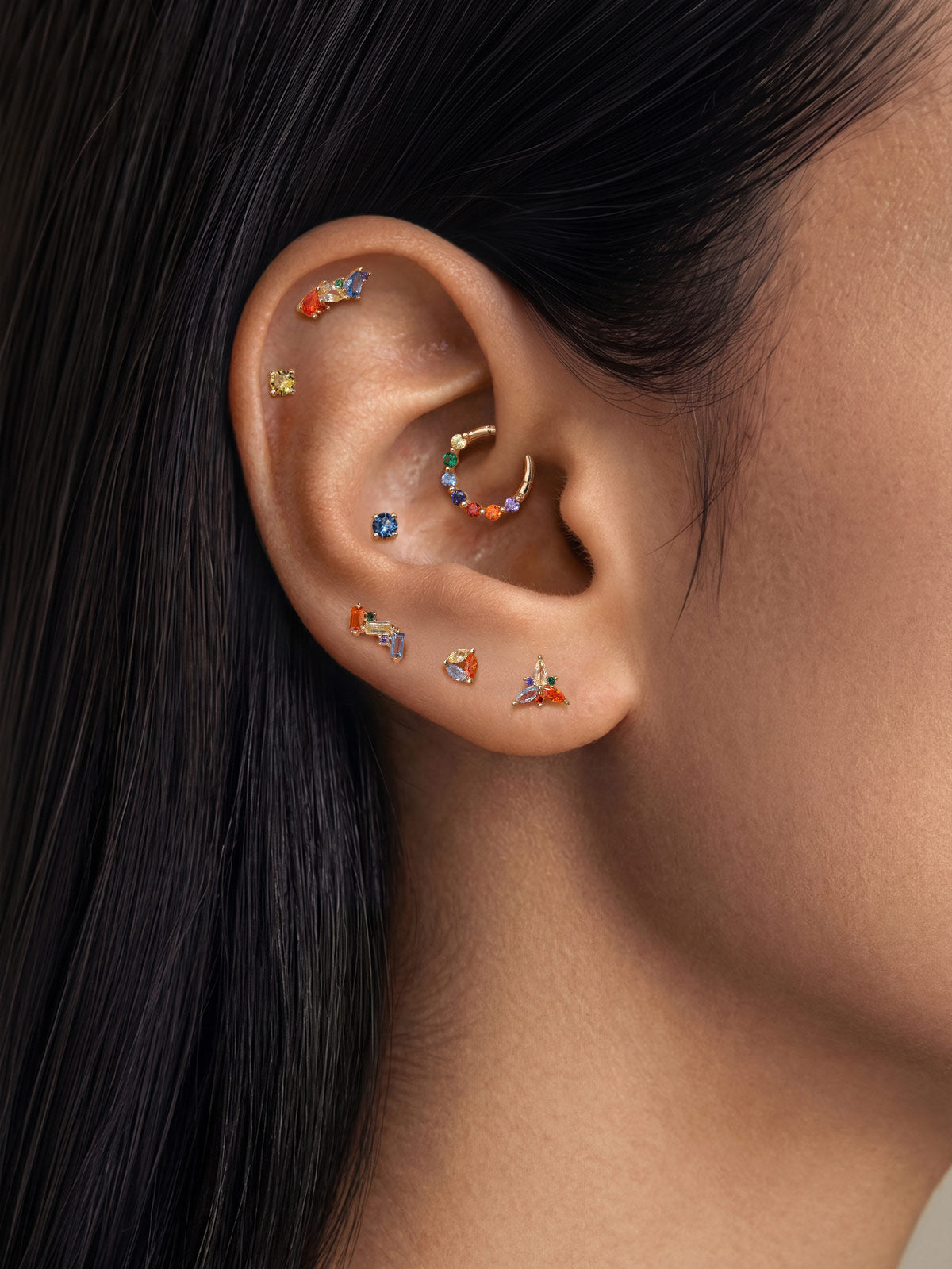 Layered ear stacking styling with KOSINER rainbow light piercing jewelry collection, triangular flower flat back studs matched with hoops for multi-position helix lobe tragus