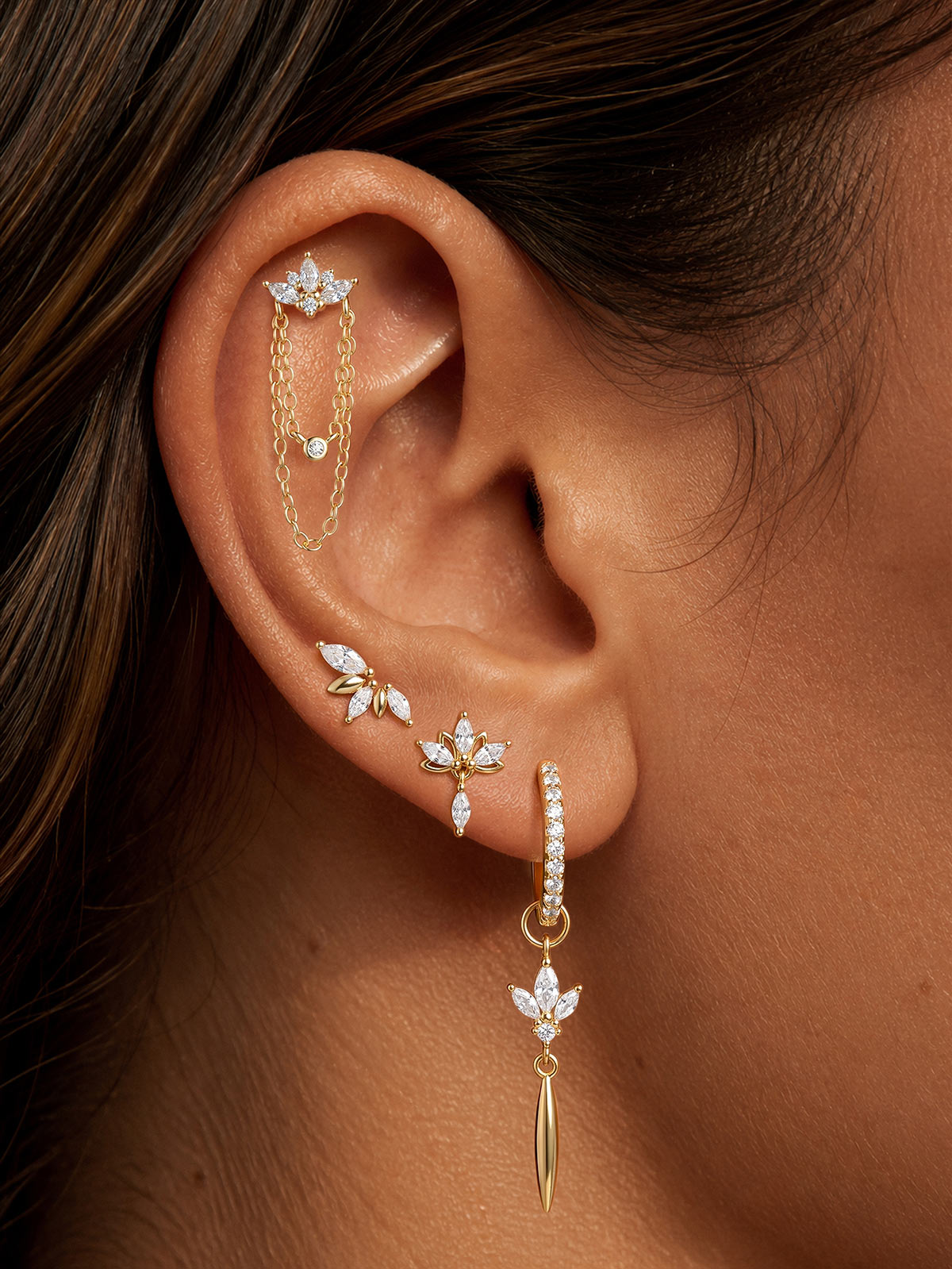 Model wearing KOSINER lotus chain dangle flat back stud in a gold ear stack