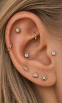 Elegant curated ear styling with KOSINER Étoile quadrilateral textured flat back stud on earlobe, matched with sunburst, leaf, triangular gem studs and gold hoop rings, refined minimalist multi-piercing daily look