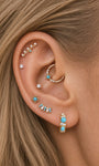 Boho curated ear styling with KOSINER Étoile turquoise sun daith clicker installed in daith piercing, matched with matching turquoise clover studs, linear gem studs and turquoise hoop earrings, cohesive radiant themed multi-piercing layout