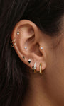 Stylish layered full ear stacking aesthetic with KOSINER Puzzle staggered black white pave cz sterling silver hoop earring, paired tiny cz cartilage studs, geometric two-tone triangle studs, plain polished gold huggie hoop, modern asymmetrical contrast detail everyday ear styling