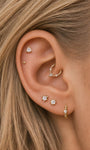 Soft minimalist curated multi-piercing ear stack featuring KOSINER Perléa beaded hoop on earlobe, styled with star-shaped crystal studs, tiny ball stud and decorative helix hoop, elegant everyday layered ear piercing design