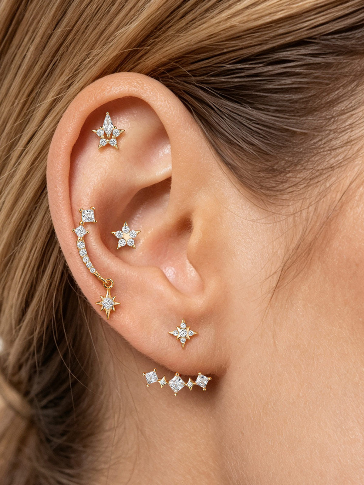KOSINER Rising Star gold-plated curved earring on a cream background showing its star stud, ear jacket and butterfly back