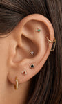 Curated multi-piercing ear styling featuring KOSINER hand hammered four-petal flower flat back stud on upper helix, matched with suit-symbol studs, star cartilage stud, chain linked ear cuff and textured hoop, sophisticated layered ear stack design