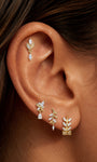 Model wearing KOSINER olive branch pear drop flat back stud in a botanical ear stack