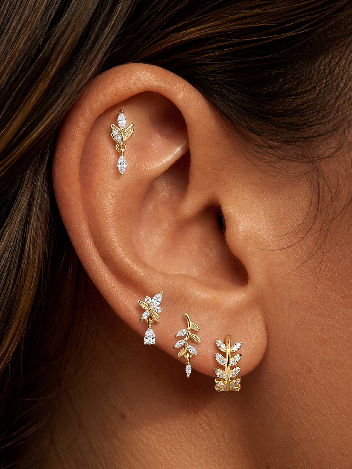 Model wearing KOSINER olive branch pear drop flat back stud in a botanical ear stack