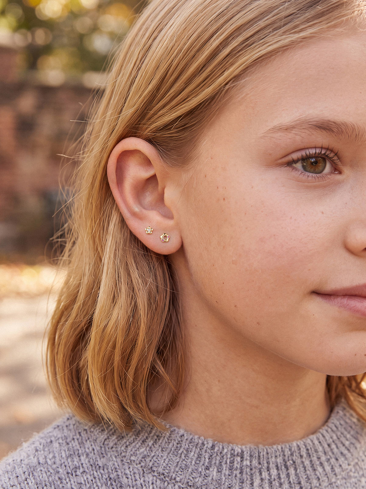 Model wearing the Little Wonder 14K gold flower flat back stud in a curated ear stack