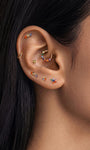 Layered ear stacking look with KOSINER rainbow light series piercing jewelry, featuring colorful baguette flat back studs for multi-position helix, tragus and lobe styling