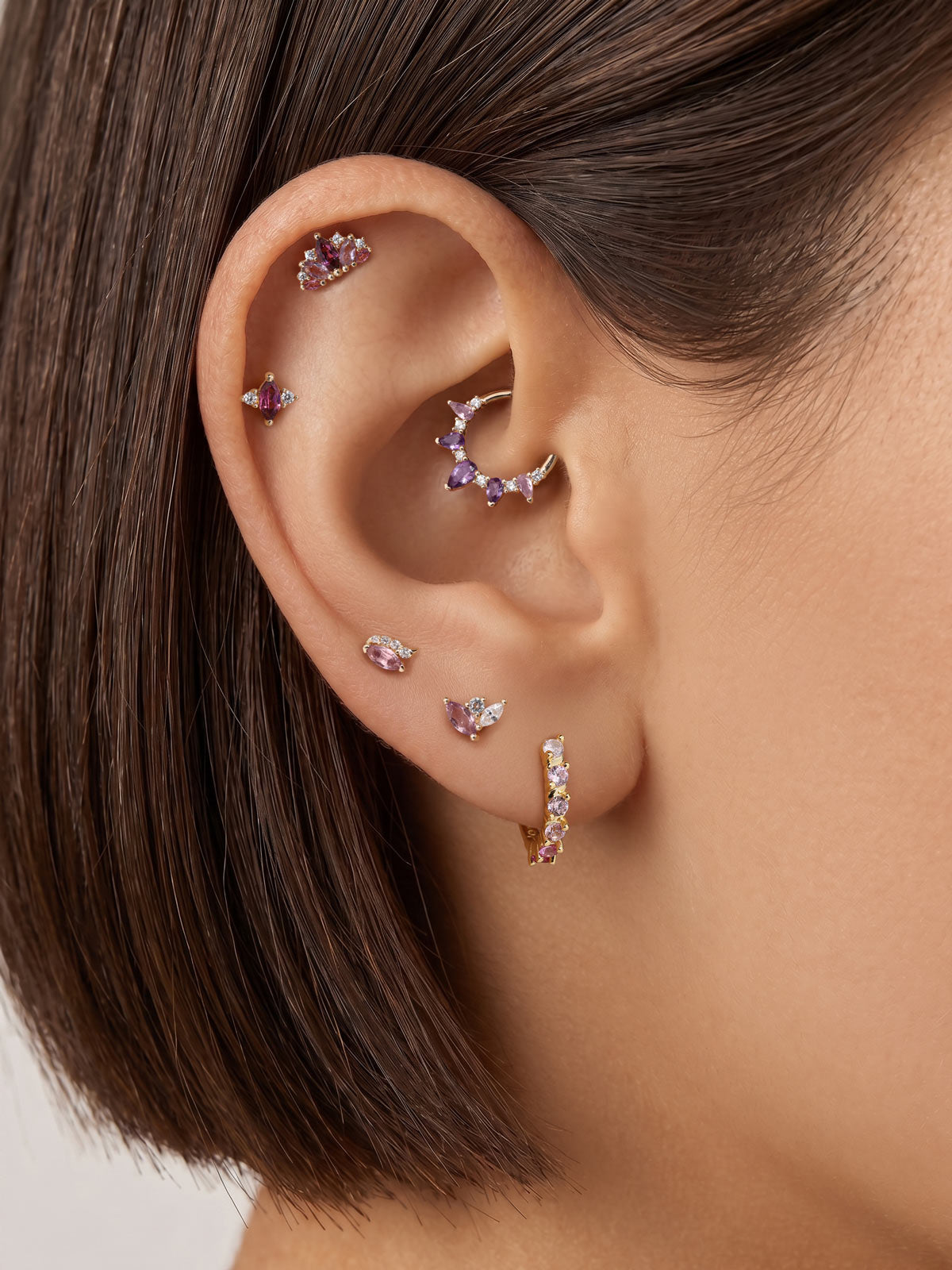 Layered full ear stack styling with KOSINER Gem Garden purple gem series, three-tone trio cluster 14K gold flat back stud matched with crown, marquise, twisted square purple cartilage piercings